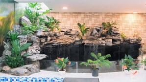 A rock waterfall feature with potted plants and a tiled floor. - Quy Tai Premium Hotel (Xuan Huong - Da Lat)