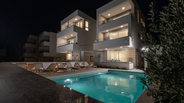 A modern multi-story building with a swimming pool and lounge chairs. - Apartments Mare B with pool  (Novalja)