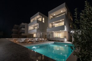 Un edificio moderno de varios pisos con piscina y sillones de descanso.