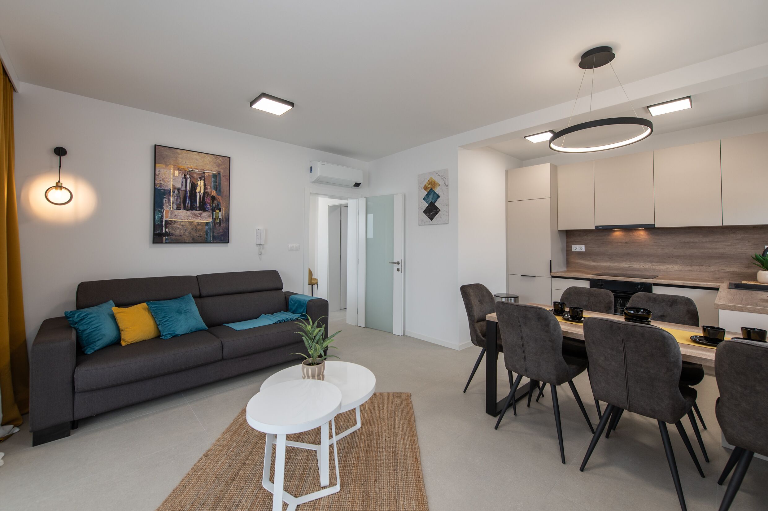A modern living room with a sofa, coffee table, and dining area with chairs and a table.