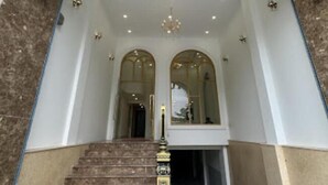 The entrance of the Hala Hotel with a grand arched doorway, a staircase leading up, and a chandelier above. - Hala Hotel - by Bay Luxury (Ho Chi Minh City)