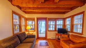 A cozy living room with wooden floors, a sofa, a coffee table, and a TV. - Private Sauna · Oceanfront Cabin w/ Views! Steps to the Beach! ⎮Hidden Pearl (Ucluelet)