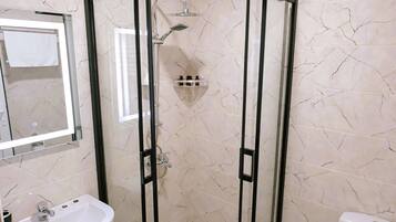 A bathroom with a glass-enclosed shower, a pedestal sink, and a toilet.