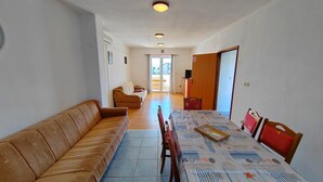 Ein Wohnzimmer mit einer Couch, einem Esstisch, Stühlen und einem Fernseher.