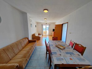 A living room with a sofa, dining table, chairs, and a TV.