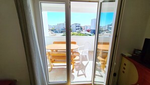 Ein Zimmer mit einer Schiebetür und einem Balkon, ausgestattet mit einem Holztisch und Stühlen.