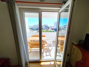 A room with a sliding glass door leading to a balcony with a wooden table and chairs.