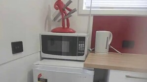 Une petite cuisine équipée d’un four à micro-ondes, d’un petit réfrigérateur et d’une machine à café, le tout installé sur un plan de travail.