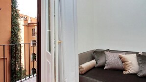 Un balcón con vistas a un edificio y un sofá con cojines.