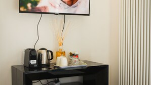 Una cocina moderna equipada con televisión integrada, cafetera, hervidor, refrigerador y contenedor de basura.