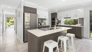 A modern kitchen with a central island, stainless steel appliances, and a view of the outdoors.