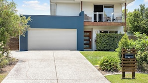 A two-story house with a garage, a balcony, and a well-maintained lawn.