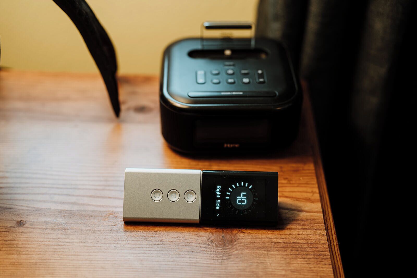 A portable speaker and a portable phone charger on a wooden table.