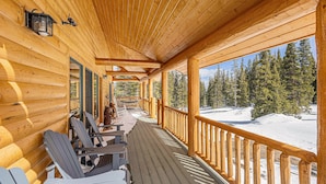 A wooden deck with chairs and a view of a snowy landscape. - Log Cabin on 10 Acres with Loft and Soaker Tub. (Fairplay)