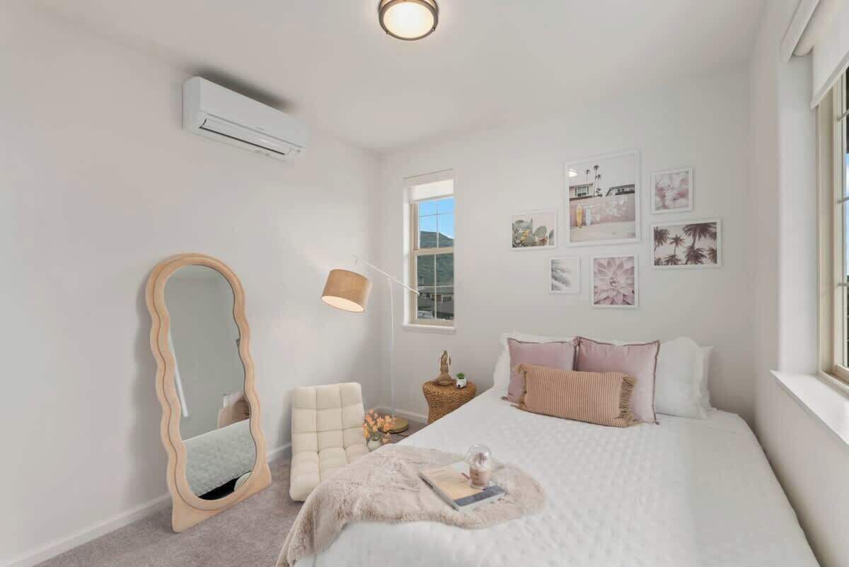 Un dormitorio con cama, una silla, un espejo y decoración en la pared.