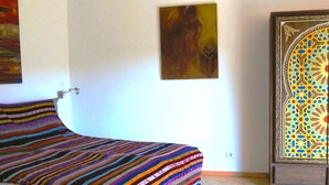 Een slaapkamer met een bed, een schilderij en een decoratief wandobject.