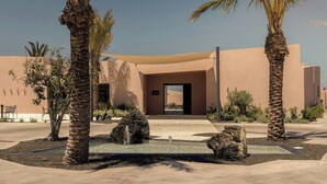 A building with a modern architectural style, featuring a flat roof and a large entrance. - Domes Novos Santorini, Autograph Collection (Santorini)
