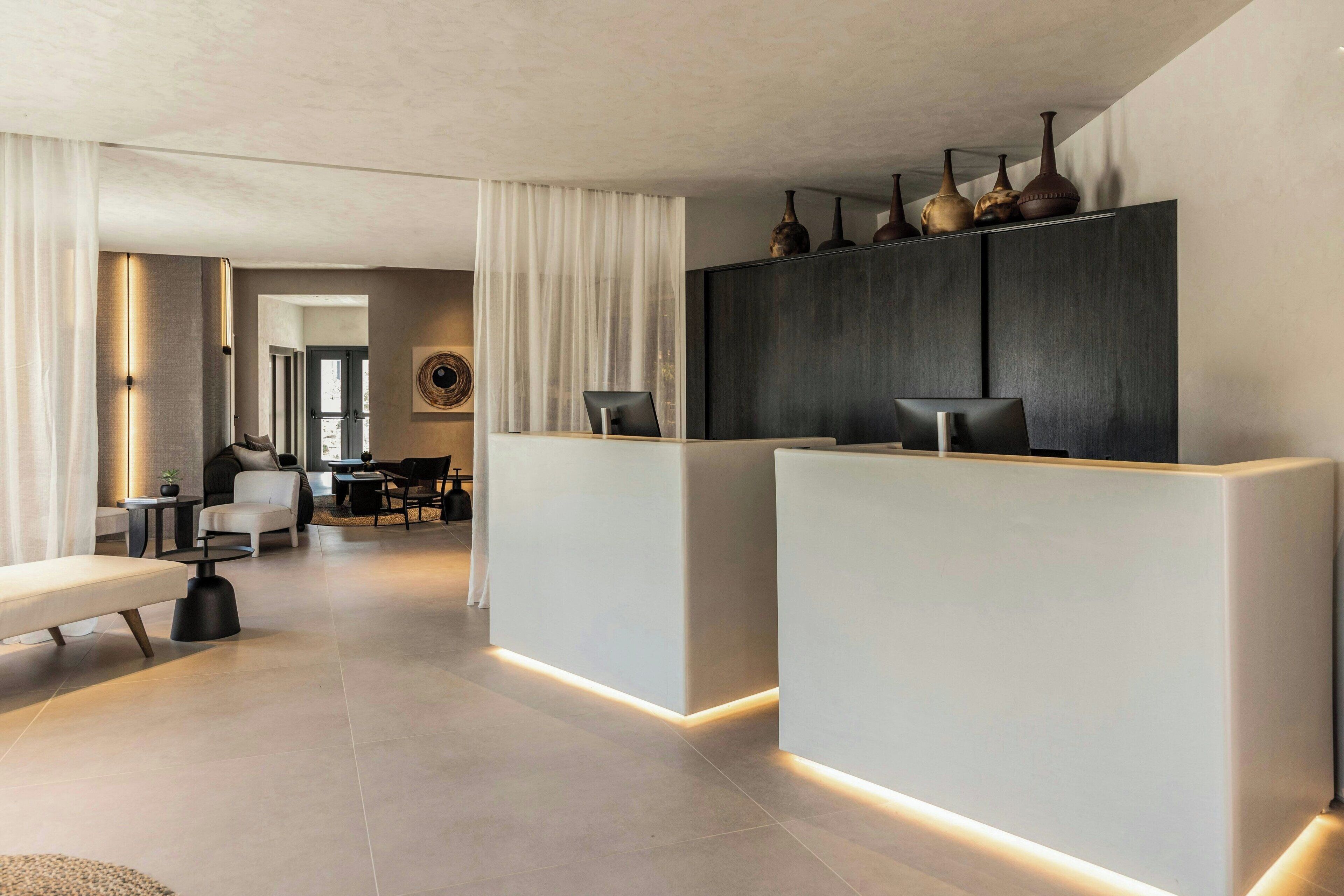 A modern reception area with a minimalist design, featuring a reception desk, seating area, and a view into the adjacent room.