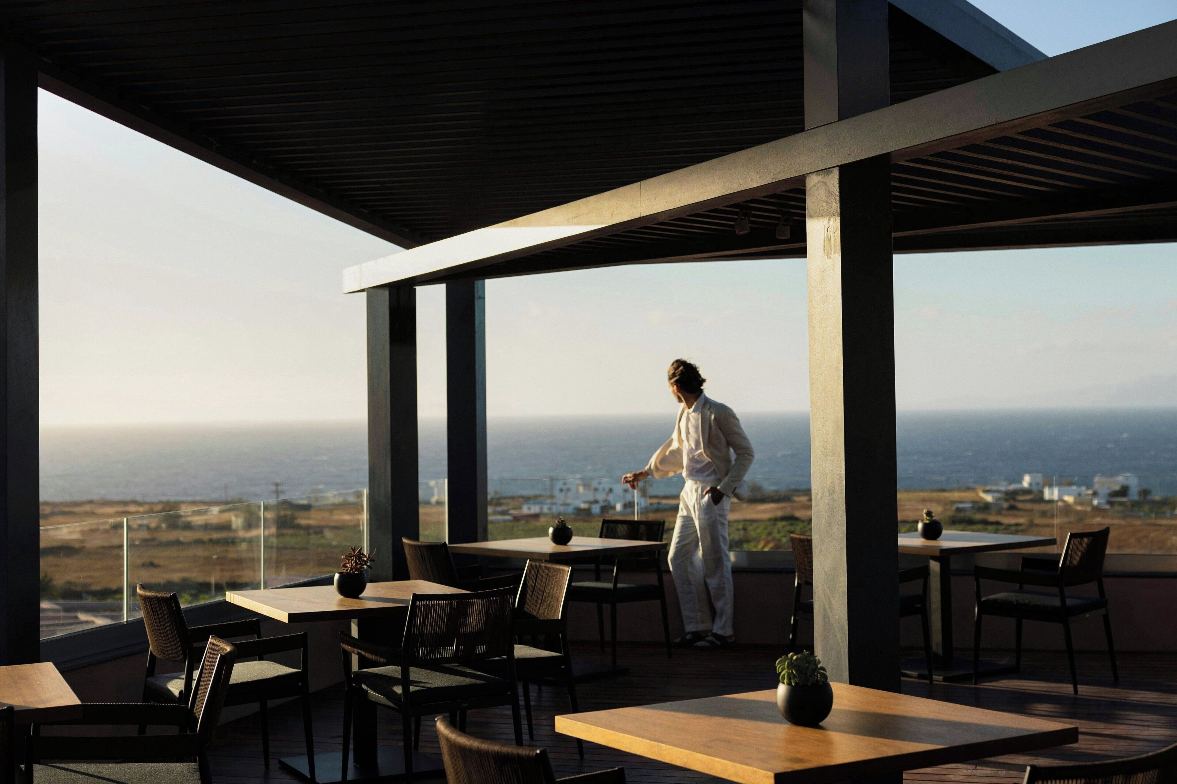 Restaurant amb terrassa a l'aire lliure que dona al mar, amb un cambrer atent als clients.