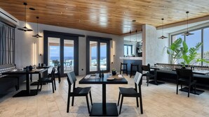 Ein moderner Essbereich mit Holzboden, großen Fenstern und Blick auf das Meer.