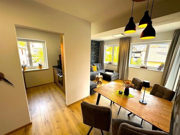 Una cocina moderna con horno integrado y comedor con mesa y sillas de madera.