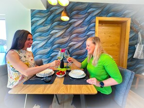 Ein Essbereich mit einer modernen Wand im Wellenmuster, Holzmöbeln und einem Tisch, der mit Tellern, Gläsern und einer Schale Erdbeeren gedeckt ist.