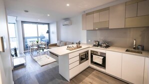 A modern kitchen with a central island, built-in oven, and stainless steel appliances.