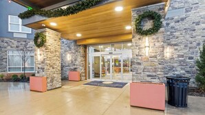 A hotel entrance with stone walls, a wooden ceiling, and a glass door leading inside.