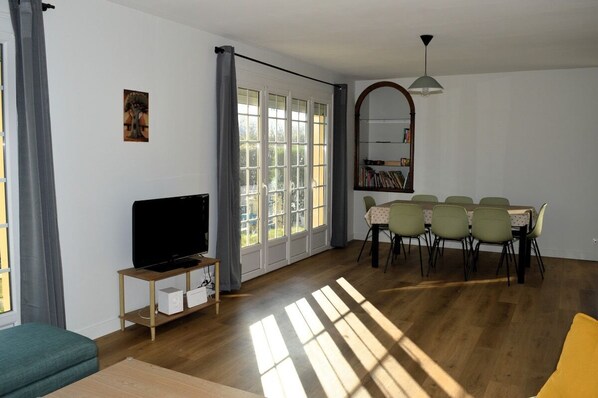 Un salon avec un téléviseur, une table à manger et des chaises.