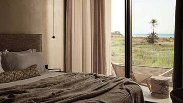 Un dormitorio con una cama grande, vistas a la playa y un balcón con una silla.
