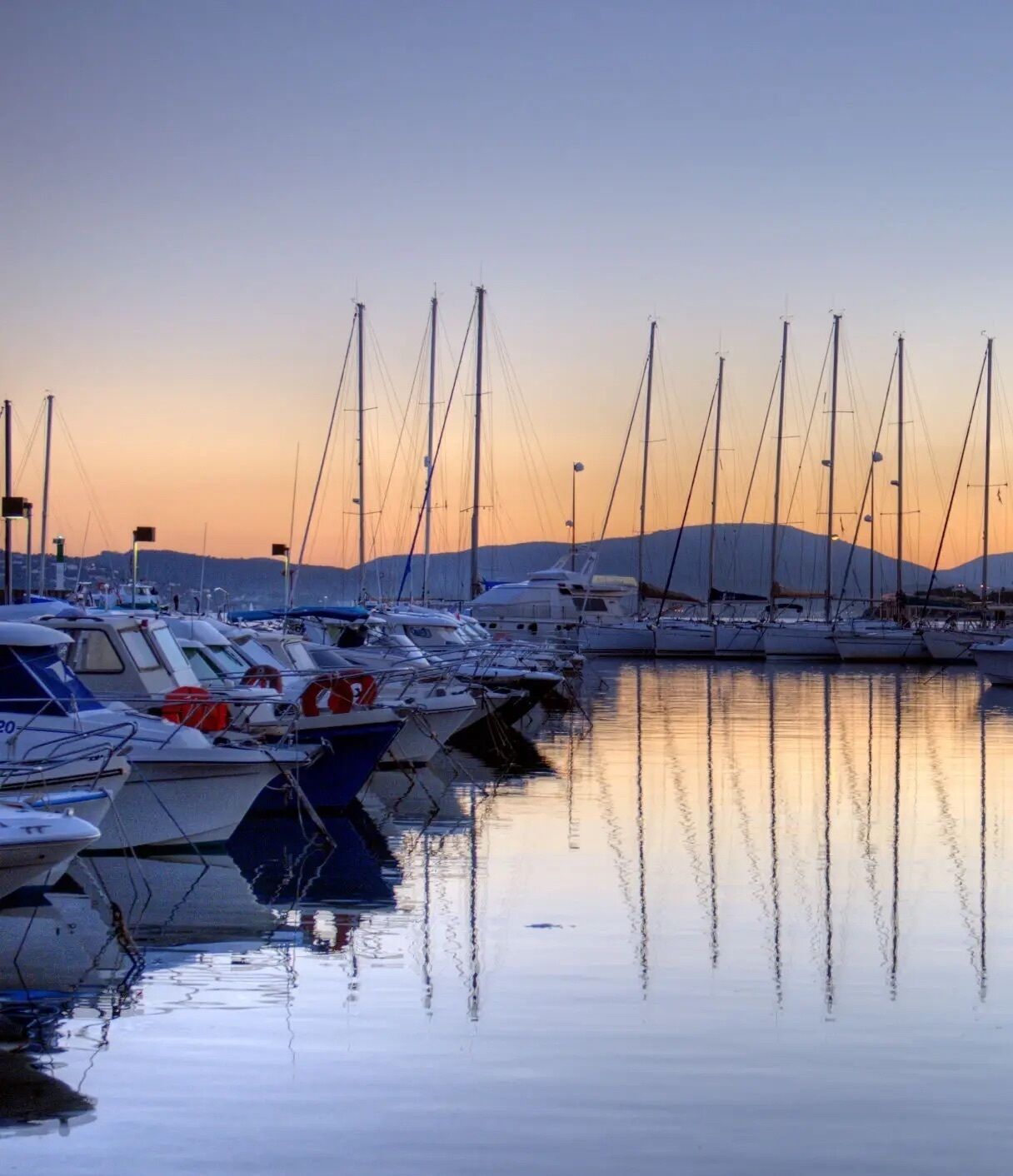 A marina with multiple boats docked at sunset.