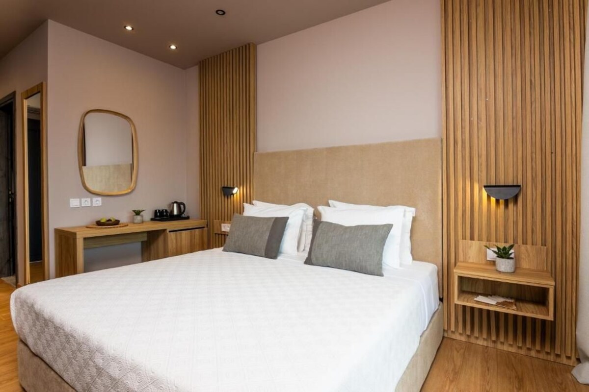 A modern hotel room with a large bed, bedside tables, a desk, and a mirror.