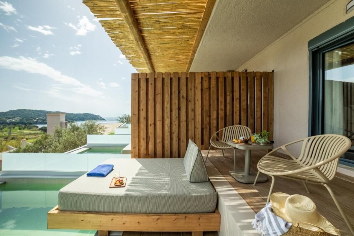 Un balcon avec un plancher en bois, un lit, une table et deux chaises.