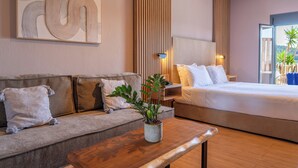 Ein modernes Hotelzimmer mit einer Couch, einem Bett, einem Holztisch, einer Topfpflanze und einem großen, abstrakten Kunstwerk an der Wand.