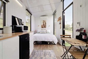A modern bedroom with a bed, bedside table, and a large window. - Acre Away by Tiny Away (Kangaroo Ground)
