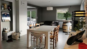 Un soggiorno moderno con zona pranzo, divano, tavolino e un'ampia finestra vista su spazi verdi.