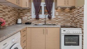 Una cocina compacta con armarios de madera, horno integrado y lavadora.