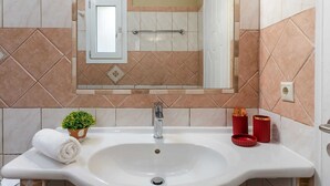 Un baño con un lavabo blanco, un espejo y una toalla.