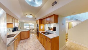 A modern kitchen with wooden cabinets, granite countertops, and a central island. - Views of Osprey Lake in Pelican Watch 4 Bedroom (Pawleys Island)