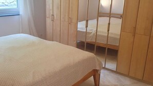 A bedroom with a bed, a wardrobe, and a window. - Ruhige Ferienwohnung am Stadtrand von Lindau Inmitten von Wiesen und Obstbäumen (Lindau (Bodensee))