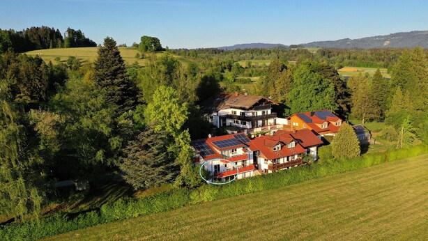 A residential area with houses featuring red roofs and solar panels, surrounded by lush greenery and trees. - Ruhige Ferienwohnung am Stadtrand von Lindau Inmitten von Wiesen und Obstbäumen (Lindau (Bodensee))