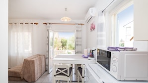 A compact kitchen with a dining area, a sofa, and a view through the window. - Cozy Apartment Marija With Garden (Novalja)