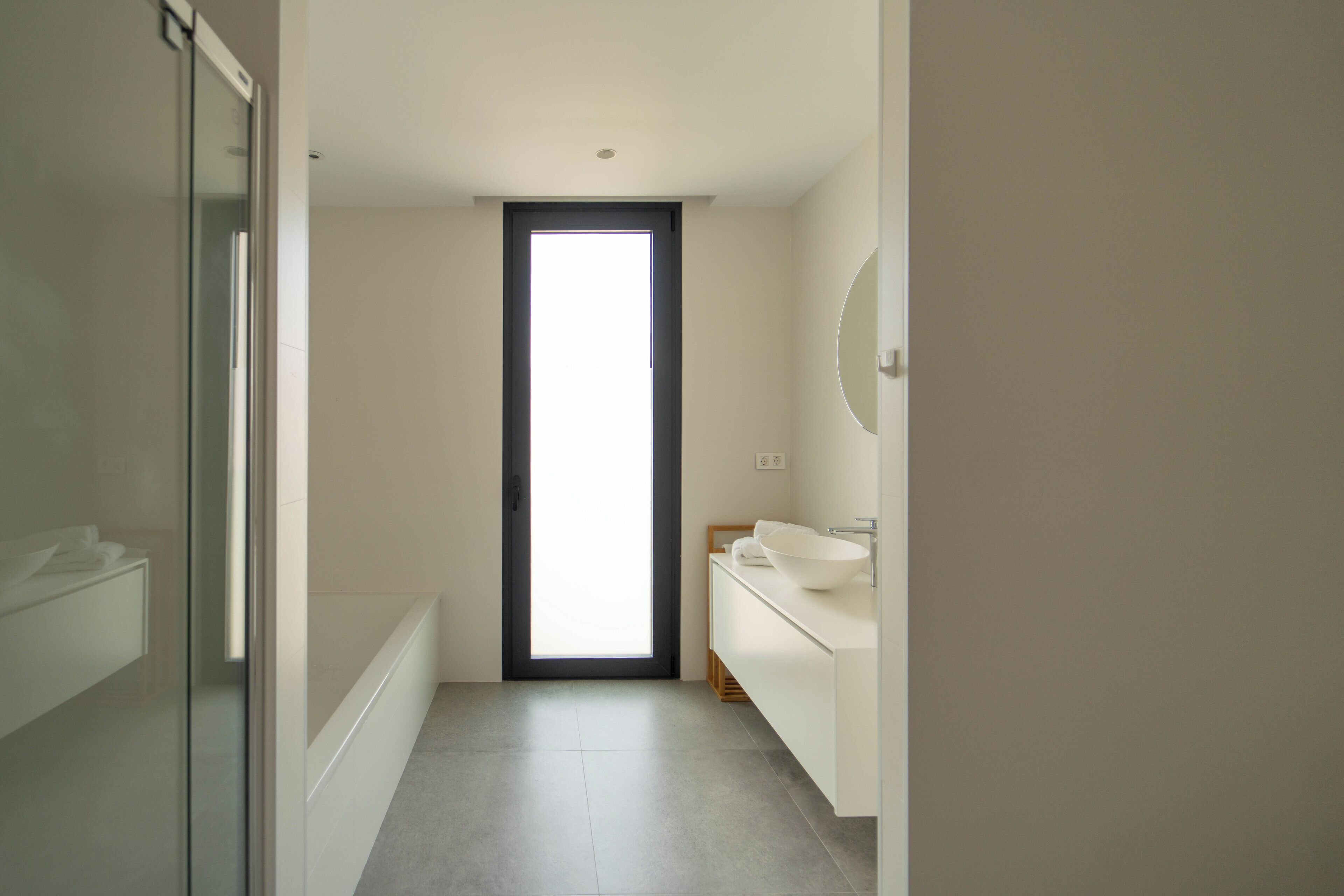 A modern bathroom with a large window, a white sink, and a mirror.