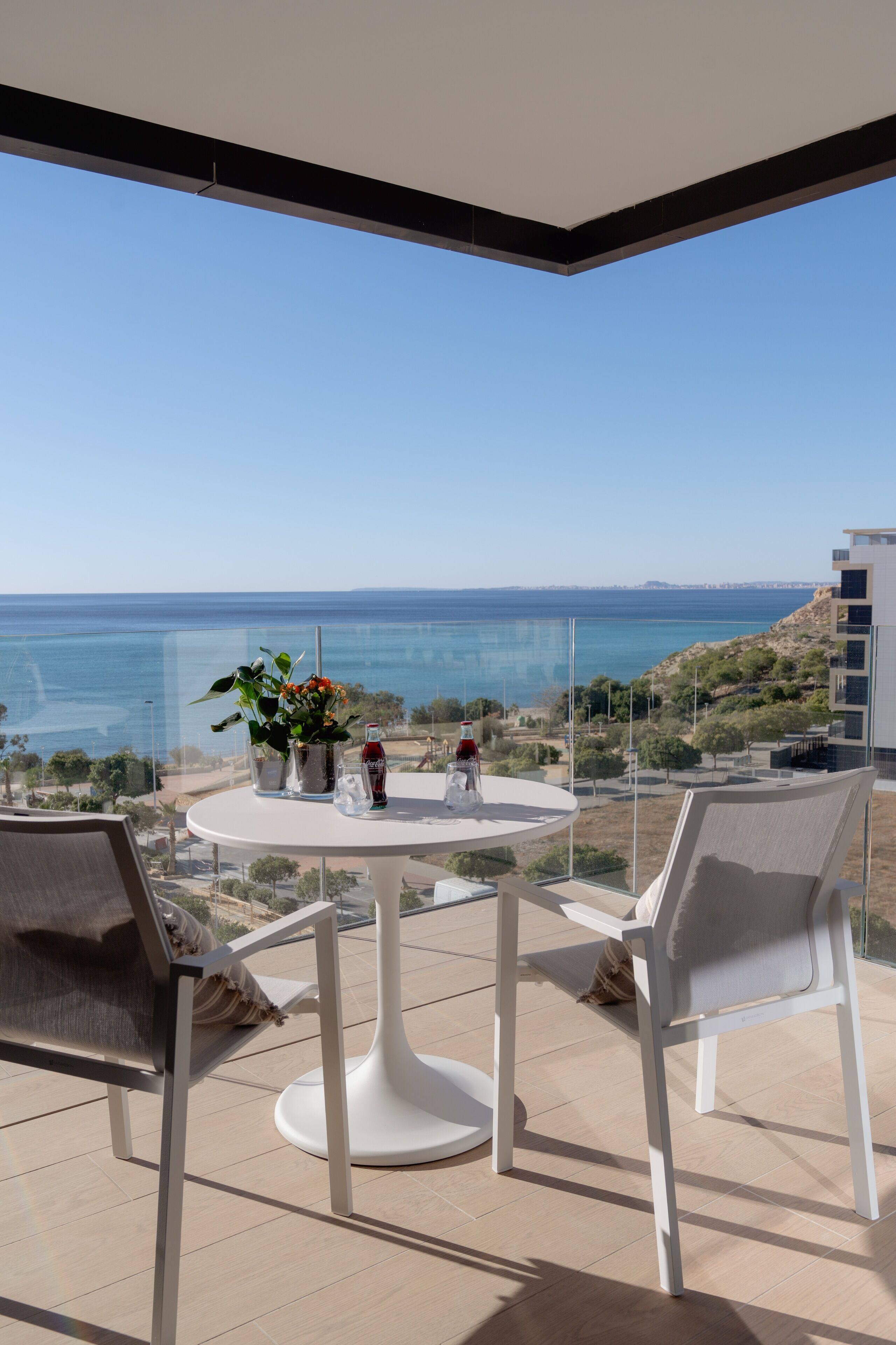 Un balcón con mesa, sillas y vista al mar.