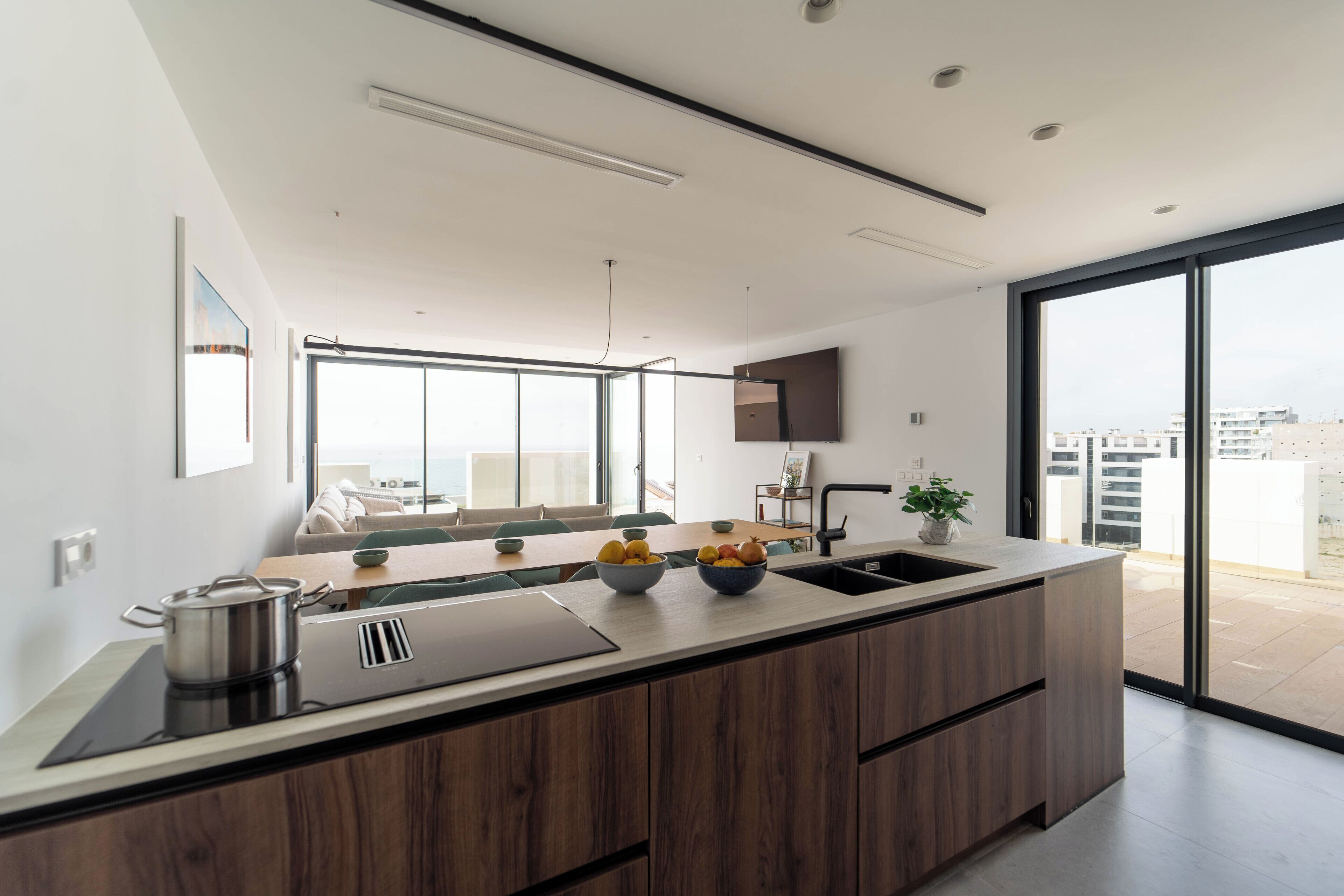 A modern kitchen with a large island, a sink, and a dining area with a table and chairs.