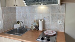 A kitchen with a stainless steel sink, a gas stove, and a tiled backsplash. - Stefanos Home - Apartment 1 (Kefalonia)