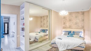 A modern bedroom with a large mirror, a bed with blue and white bedding, and a wooden floor. - HB apartments Aghmashenebeli III (Tbilisi)