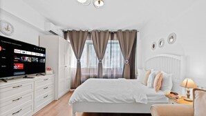 A modern bedroom with a bed, a TV, a dresser, and a window with curtains. - Sudului 507 by MRG Apartments (București)