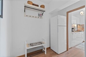 A kitchen with a white refrigerator, a bench with a patterned cushion, and a 'No Smoking' sign on the wall.