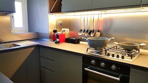 A modern kitchen with a gas stove, a pot on the burner, and various utensils hanging above the counter.